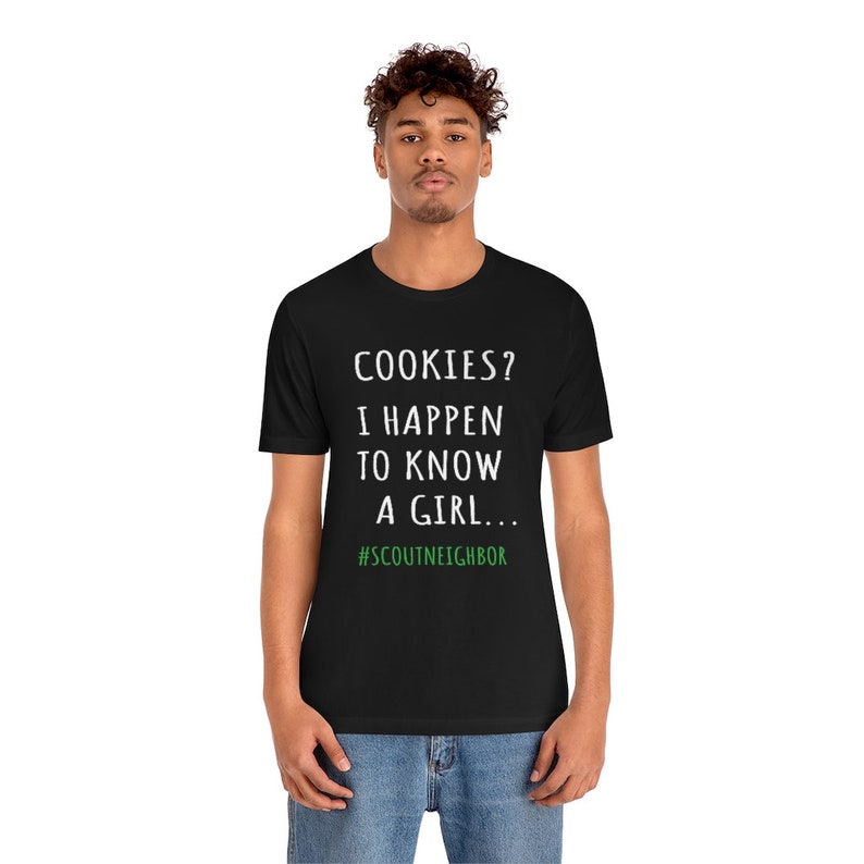 May include: A black t-shirt with white text that reads "COOKIES? I HAPPEN TO KNOW A GIRL... #SCOUTNEIGHBOR".