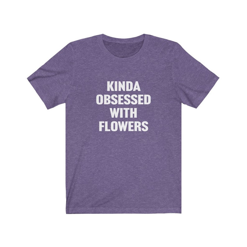 Puede incluir: Camiseta de manga corta de color morado con el texto "Kinda obsessed with flowers" en blanco.