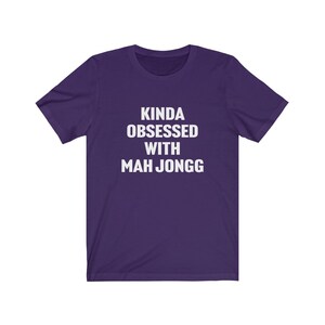 May include: Purple short-sleeved t-shirt with white text that reads "Kinda obsessed with Mah Jongg".