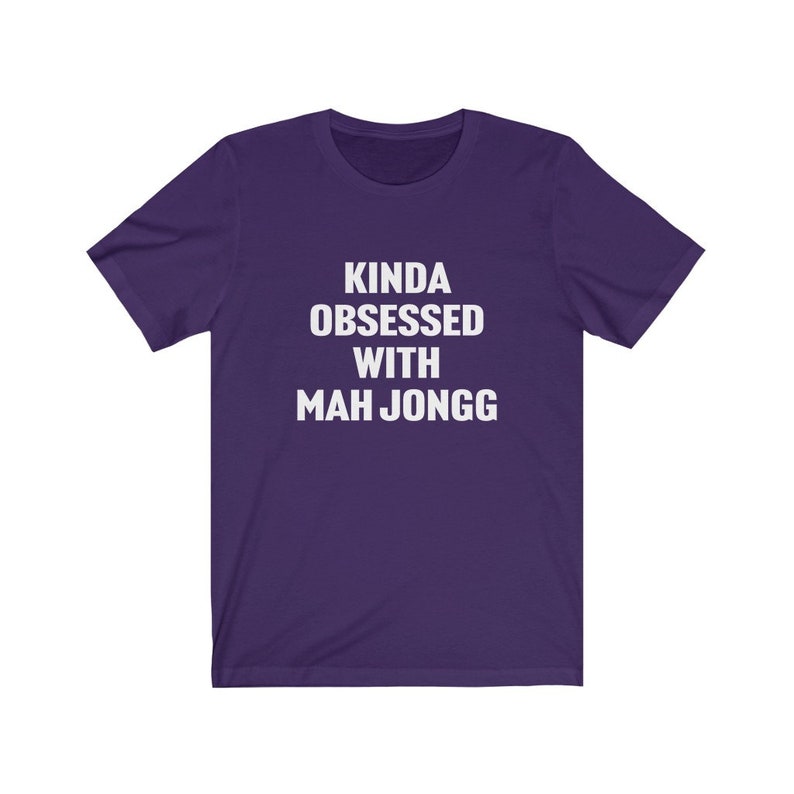 May include: Purple short-sleeved t-shirt with white text that reads "Kinda obsessed with Mah Jongg".