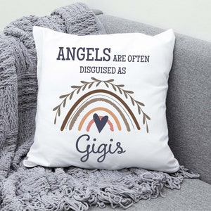 May include: White throw pillow with the text "Angels are often disguised as" and a rainbow with a heart in the center. The text "Gigis" is below the rainbow.