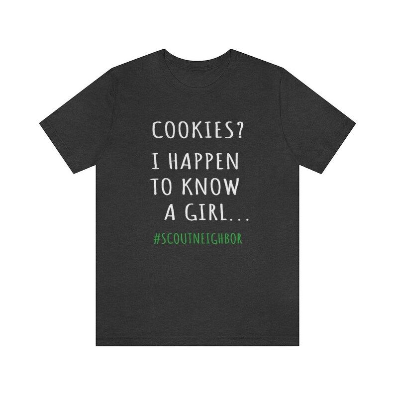 May include: Dark gray t-shirt with white text that reads "COOKIES? I HAPPEN TO KNOW A GIRL... #SCOUTNEIGHBOR".