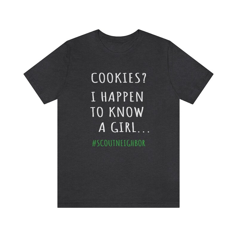 May include: Dark heather grey t-shirt with white text that reads "COOKIES? I HAPPEN TO KNOW A GIRL... #SCOUTNEIGHBOR".