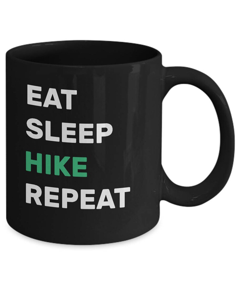 May include: Black coffee mug with white text that reads "Eat Sleep Hike Repeat". The word "Hike" is in green.