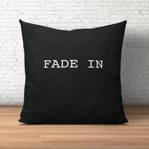 Könnte beinhalten: Schwarzes Kissen mit weißem Text "FADE IN".