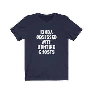 May include: A navy blue t-shirt with white text that reads "Kinda obsessed with hunting ghosts".