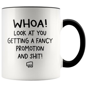 May include: White ceramic coffee mug with a black rim and handle. The mug has black text that reads "WHOA! LOOK AT YOU GETTING A FANCY PROMOTION AND SHIT!" with a fist emoji at the bottom.