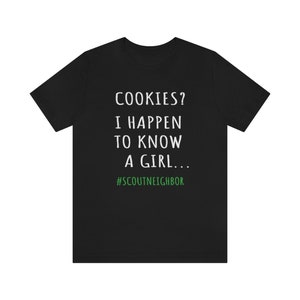 May include: Black t-shirt with white text that reads "COOKIES? I HAPPEN TO KNOW A GIRL... #SCOUTNEIGHBOR"