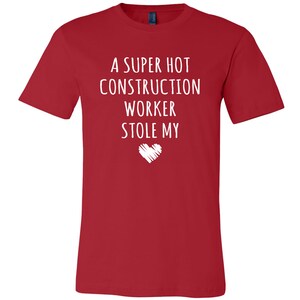 May include: Red t-shirt with white text that reads "A super hot construction worker stole my heart".