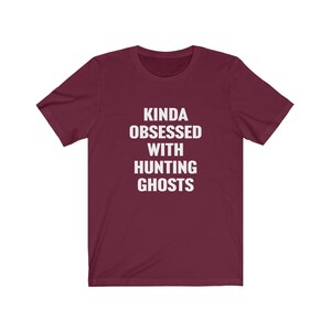 May include: Burgundy t-shirt with white text that reads "Kinda obsessed with hunting ghosts."
