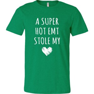 May include: A green t-shirt with the text "A super hot EMT stole my" and a white heart.
