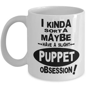 May include: White ceramic coffee mug with black text that reads "I kinda sorta maybe have a slight puppet obsession!"