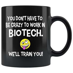 May include: Black coffee mug with white text that reads "You don't have to be crazy to work in Biotech. We'll train you!" and a yellow smiley face with a pink tongue.