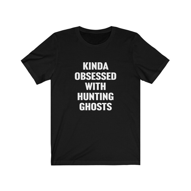 May include: Black t-shirt with white text that reads "Kinda obsessed with hunting ghosts."