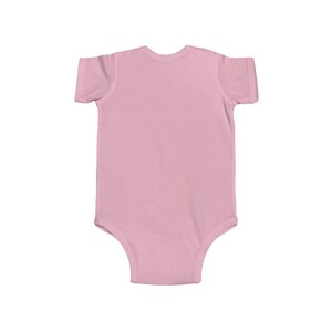 May include: A plain pink baby onesie with short sleeves.