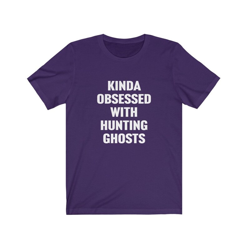 May include: Purple short-sleeved t-shirt with white text that reads "Kinda obsessed with hunting ghosts".