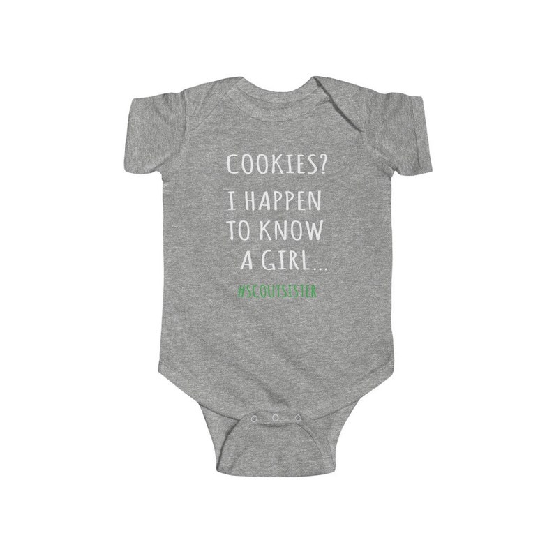 May include: Gray baby onesie with the text "COOKIES? I HAPPEN TO KNOW A GIRL... #SCOUTSISISTER" in white. The text "#SCOUTSISISTER" is in green.