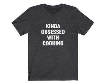 May include: A dark heather grey t-shirt with the text "Kinda obsessed with cooking" printed in white.