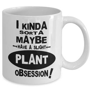May include: White ceramic mug with a curved handle. The mug features black text that reads "I kinda sorta maybe have a slight plant obsession!" in a playful font. The text is arranged in multiple lines and an oval shape.
