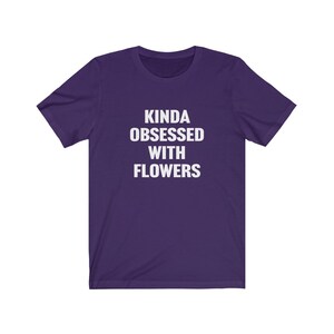 Puede incluir: Camiseta de manga corta de color morado con texto blanco que dice "Kinda obsessed with flowers".