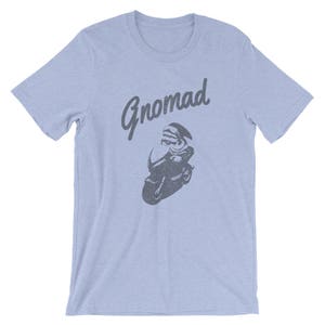 Op de afbeelding: Lichtblauw T-shirt met een afbeelding van een persoon op een motorfiets en het woord "Gnomad" in grijs gedrukt.