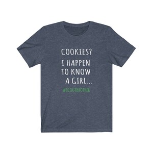 May include: A dark blue t-shirt with white text that reads "COOKIES? I HAPPEN TO KNOW A GIRL... #SCOUTBROTHER".