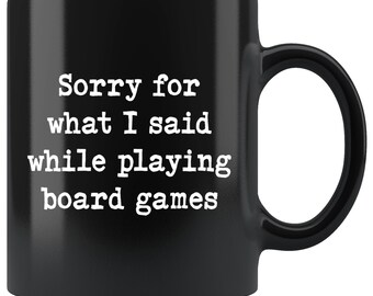May include: Black coffee mug with white text that reads "Sorry for what I said while playing board games".