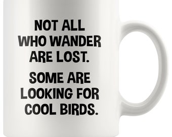 May include: White ceramic coffee mug with black text that reads "Not all who wander are lost. Some are looking for cool birds."
