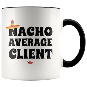 May include: White ceramic coffee mug with a black rim and handle. The mug features a black graphic of a sombrero, the text "NACHO AVERAGE CLIENT", and a red chili pepper.