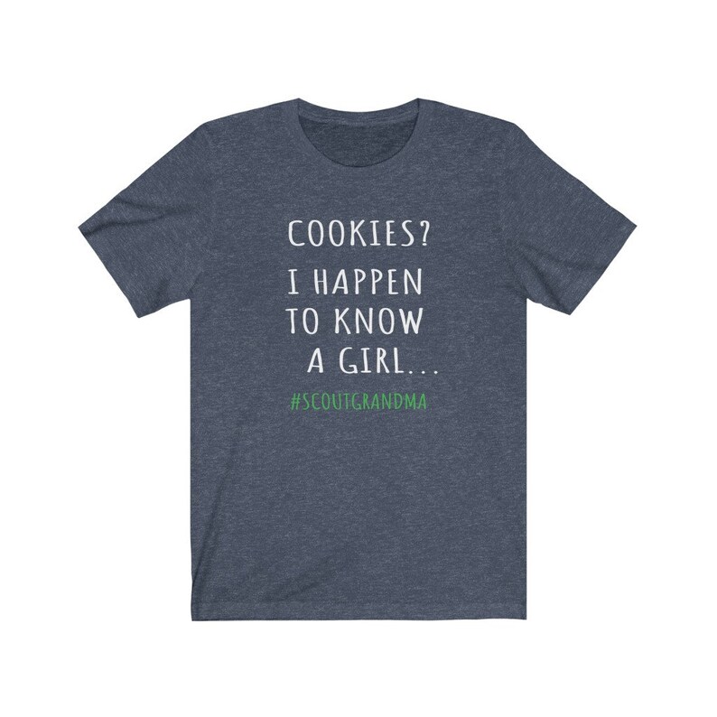 Puede incluir: Una camiseta azul oscuro con texto blanco que dice "COOKIES? I HAPPEN TO KNOW A GIRL... #SCOUTGRANDMA". El texto "#SCOUTGRANDMA" est&aacute; en verde.