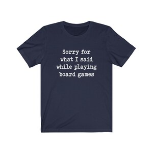 May include: A navy blue t-shirt with white text that reads "Sorry for what I said while playing board games".