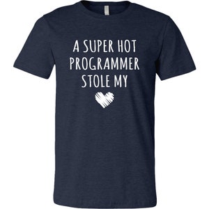 Pu&ograve; includere: Una maglietta blu navy con il testo "A super hot programmer stole my" e un grafico a forma di cuore bianco.