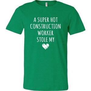 May include: A green t-shirt with the text "A super hot construction worker stole my" and a white heart.
