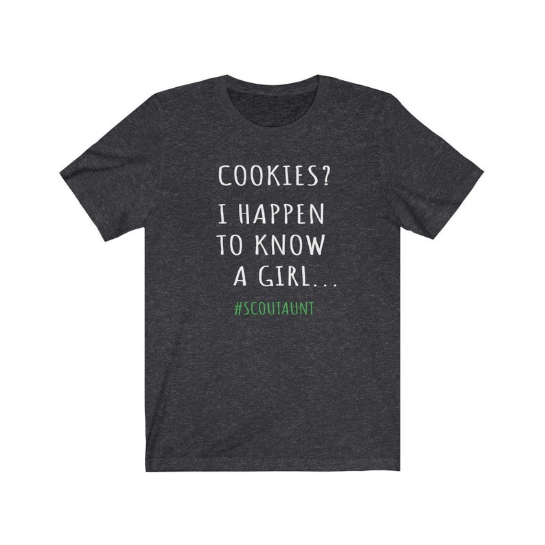 May include: A dark heather grey t-shirt with white text that reads "COOKIES? I HAPPEN TO KNOW A GIRL... #SCOUTAUNT"