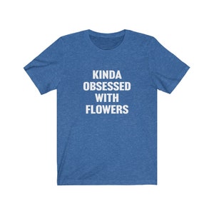 Puede incluir: Una camiseta azul con el texto "Kinda obsessed with flowers" en blanco.
