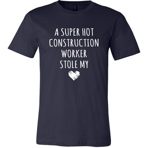 May include: A navy blue t-shirt with white text that reads "A super hot construction worker stole my heart".