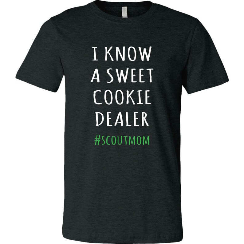 May include: A dark heather grey t-shirt with white text that reads "I know a sweet cookie dealer #scoutmom".
