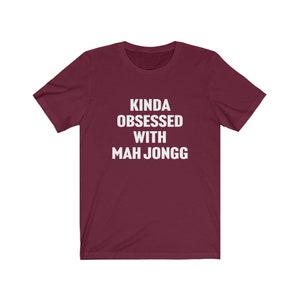 May include: A maroon t-shirt with white text that reads "Kinda obsessed with Mah Jongg".