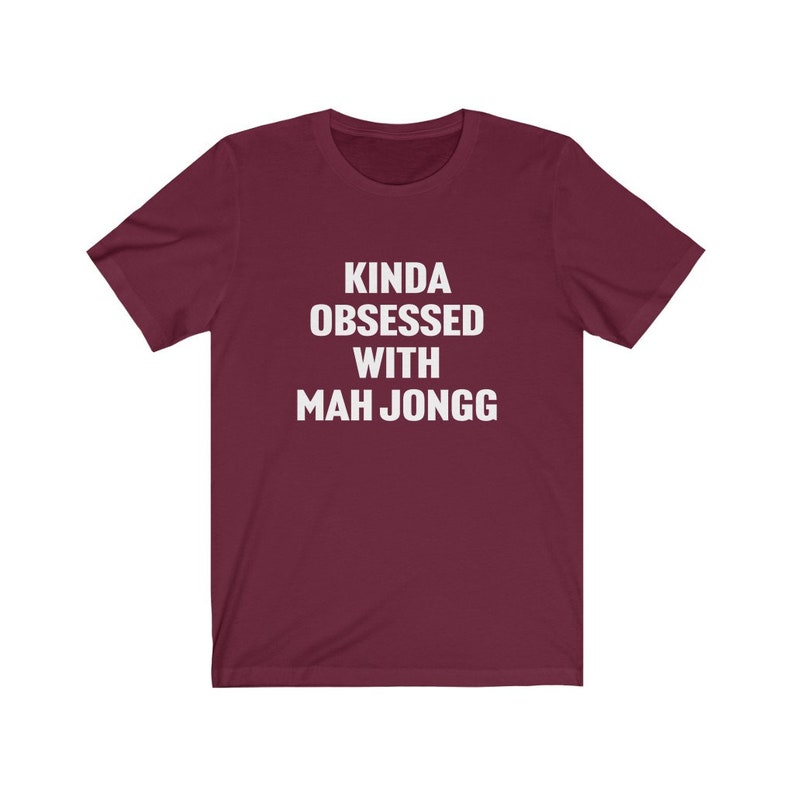 May include: A maroon t-shirt with white text that reads "Kinda obsessed with Mah Jongg".