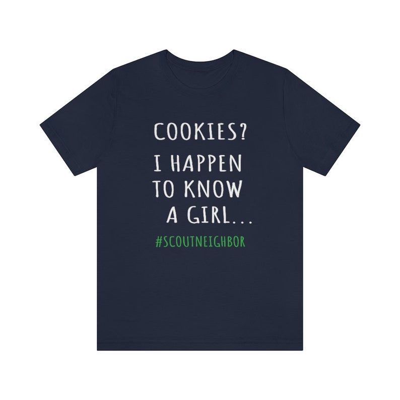 May include: Navy blue t-shirt with white text that reads "COOKIES? I HAPPEN TO KNOW A GIRL... #SCOUTNEIGHBOR".