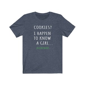 May include: A dark blue t-shirt with white text that reads "COOKIES? I HAPPEN TO KNOW A GIRL... #SCOUTAUNT".
