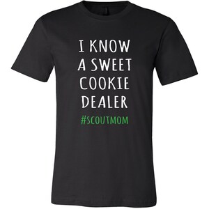 May include: Black t-shirt with white text that reads "I know a sweet cookie dealer #scoutmom" in green.
