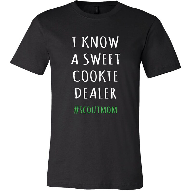 May include: Black t-shirt with white text that reads "I know a sweet cookie dealer #scoutmom" in green.