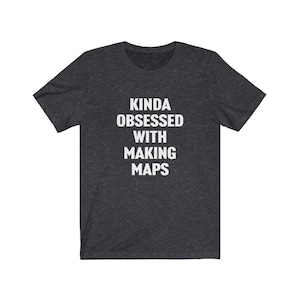 Könnte beinhalten: Ein dunkelgraues T-Shirt mit dem Aufdruck "Kinda obsessed with making maps" in Weiß.