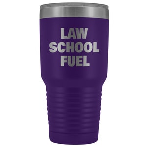 May include: Purple stainless steel tumbler with a silver inscription that reads "LAW SCHOOL FUEL".