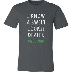 May include: A dark gray t-shirt with white text that reads "I know a sweet cookie dealer #scoutmom".