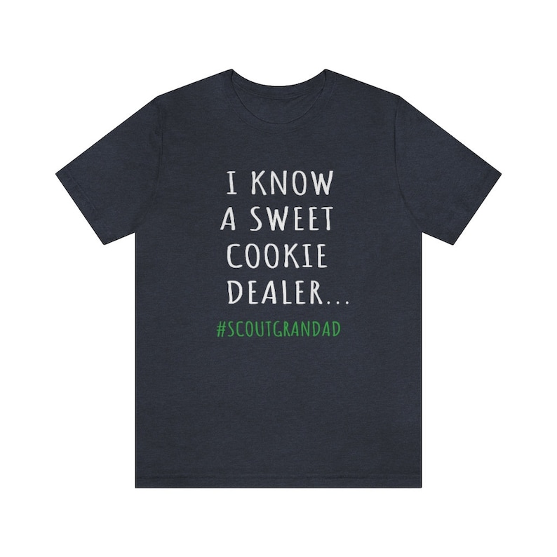 Op de afbeelding: Een donkerblauw t-shirt met witte tekst die "I know a sweet cookie dealer... #ScoutGrandad" in wit met de hashtag in groen zegt.