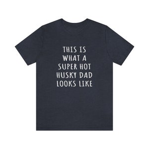 May include: A dark blue t-shirt with white text that reads "This is what a super hot husky dad looks like."