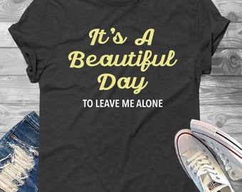 May include: A dark gray t-shirt with the text "It's A Beautiful Day To Leave Me Alone" in yellow lettering.
