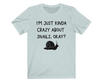 May include: A light blue t-shirt with a black snail graphic and the text "I'm just kinda crazy about snails, okay?"
